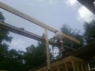 Carpenter setting a ridge beam over a new addition frame — Ice Dam Removal by Roofing Brothers in Liberal