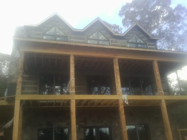 Dormers and porch framing on a large log home under construction — Roof Coating work by our crew in Liberal