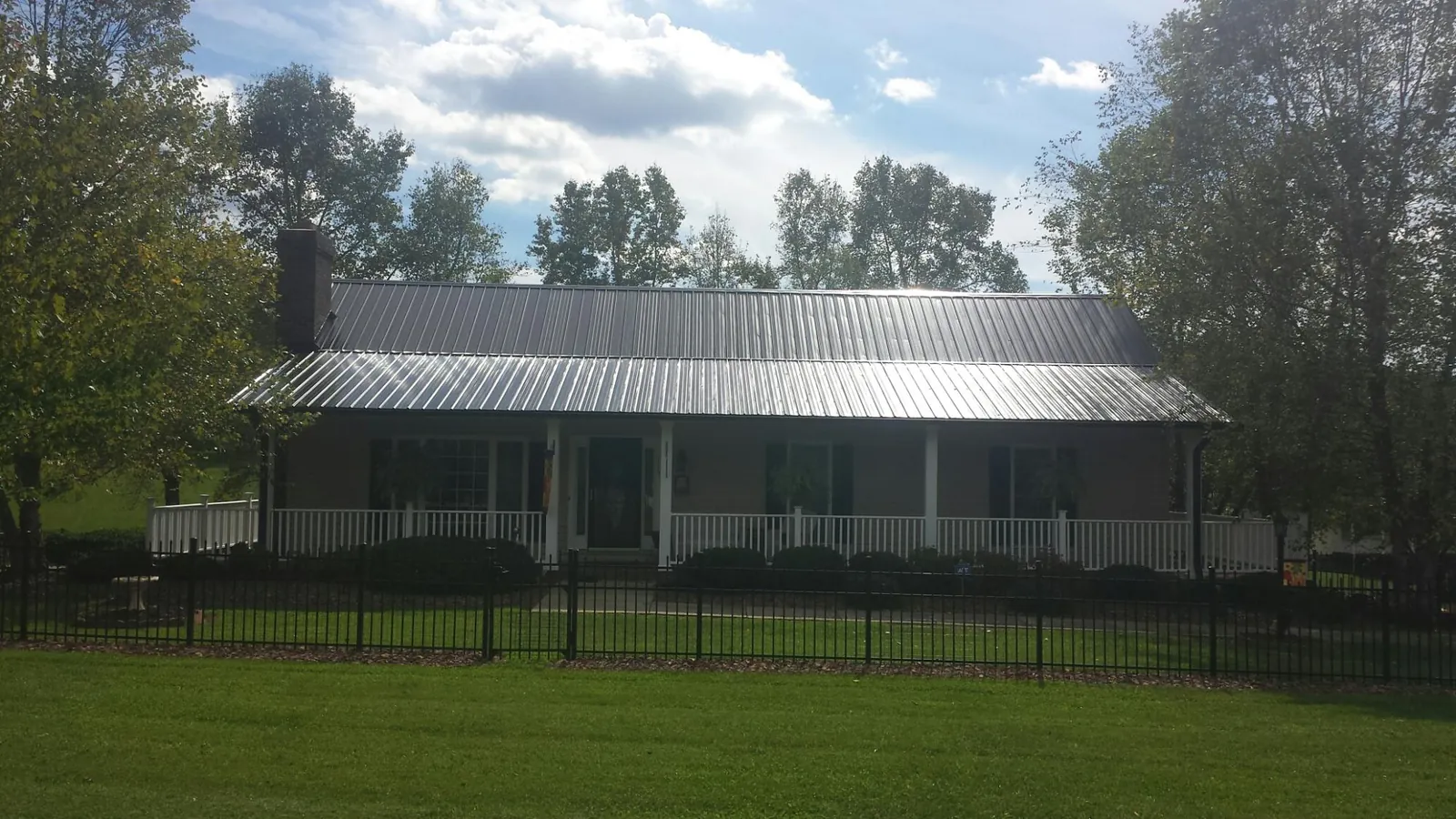 Gray metal roof on a brick ranch with a full width front porch — Gutter Guard Installation work by our crew in Liberal
