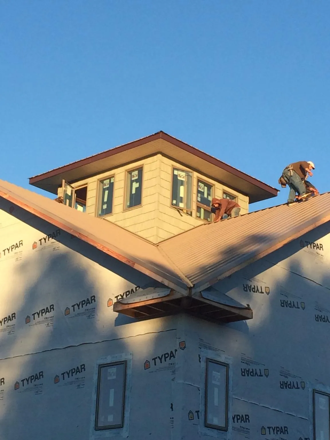 Roofers working around a rooftop cupola on a new metal roof at sunset — Roof Waterproofing in Liberal by Roofing Brothers